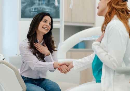 Young woman in dental office, shaking dentist's hand and smiling