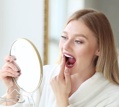 Patient in San Antonio checking their dental implants in the mirror