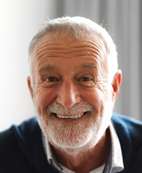 Senior man in blue shirt smiling at home