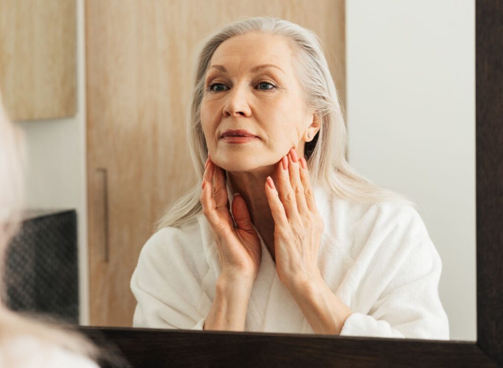 A woman examining her face in the mirror